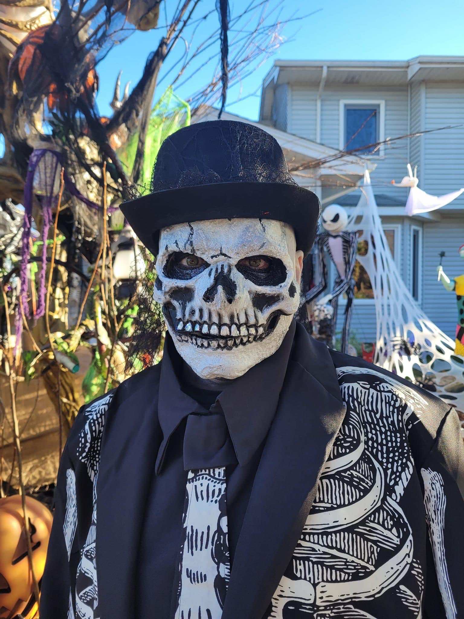 outdoors - a skeleton face in a bowler hat and skeleton shirt. cobwebs and ghosts in the background