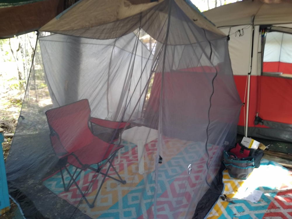 A screened area under the canopy withfolding chair and a small table.