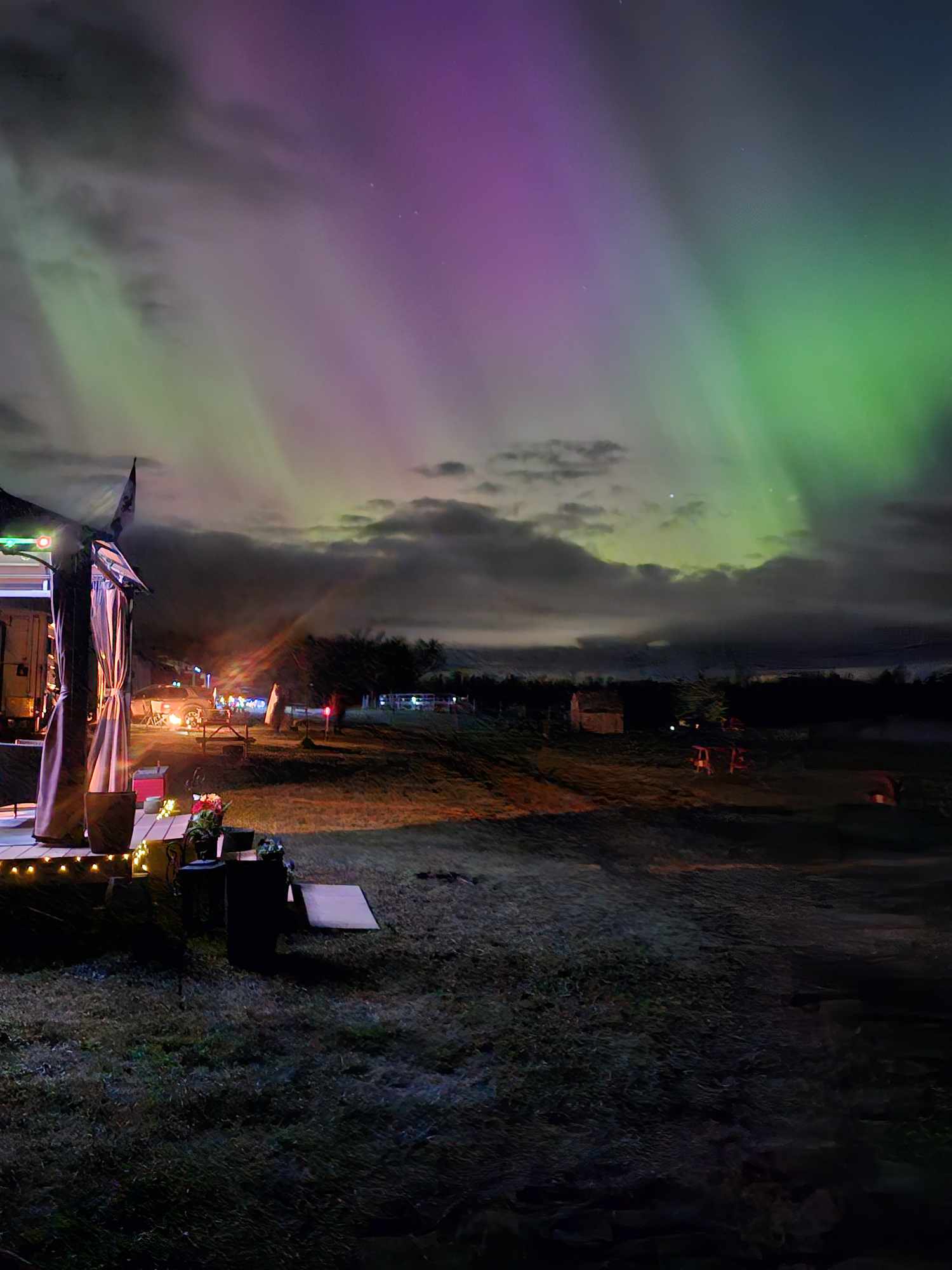 campground at night with a rainbow of northern lights above