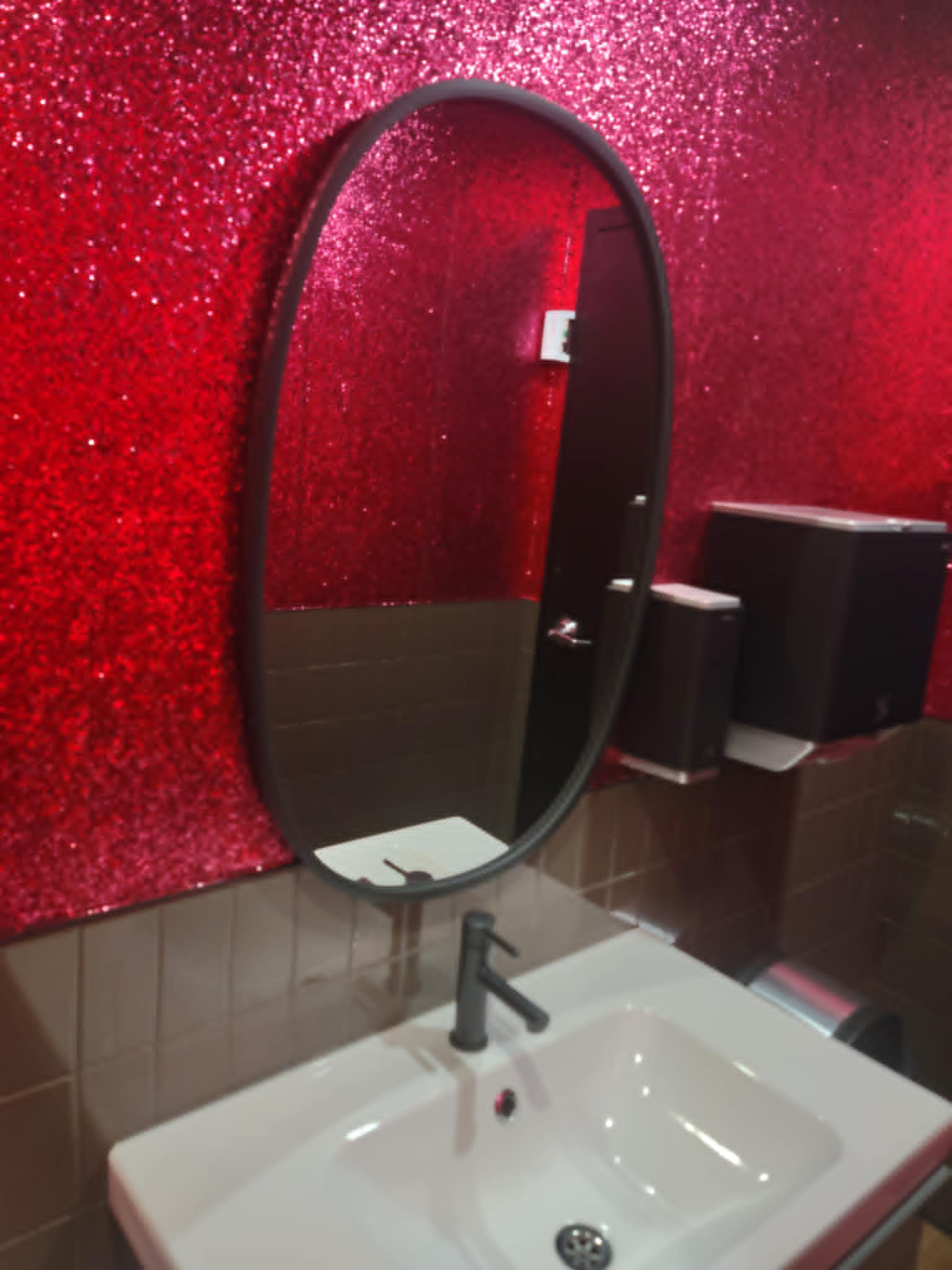 glitter walled bathroom with giant oval mirror over the sink