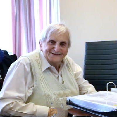 Patricia smiling at desk with a photo album in front