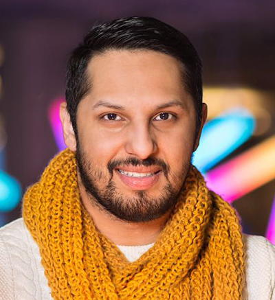 Aziz in front of rainbow lights