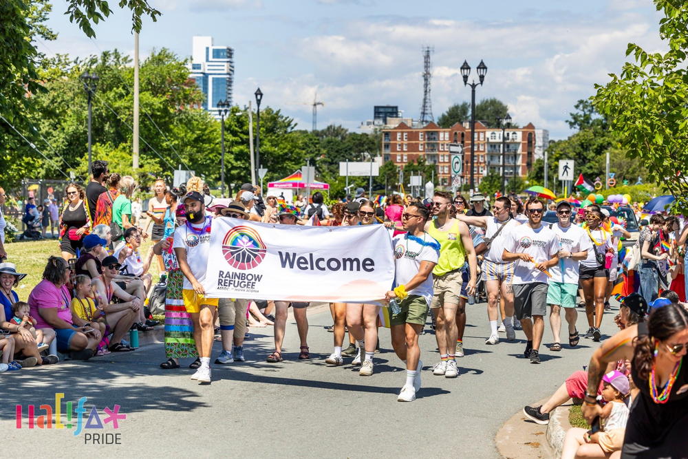 People carrying Rainbow Refugees banner in pride parade