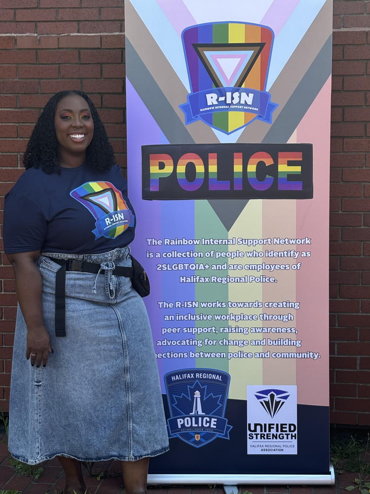 woman in a jeans skirt standing next to the R-ISN banner