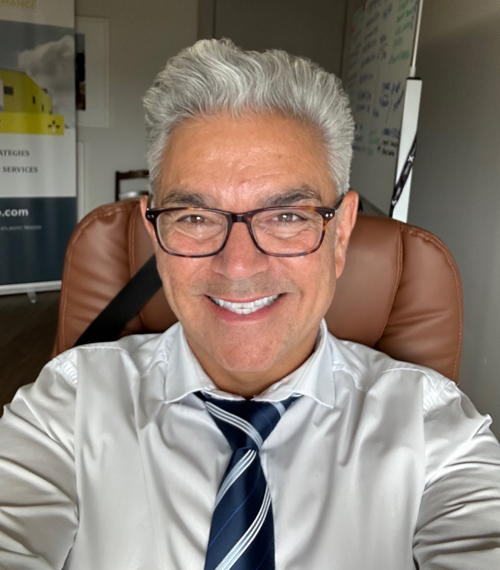 Glenn- glasses, thick white hair, white shirt and navy blue striped tie, leather chair behind