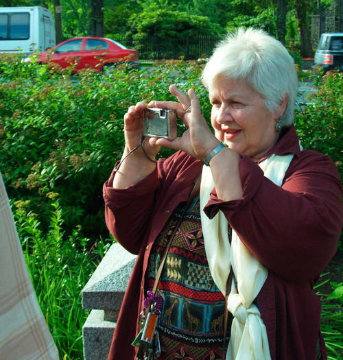 Anita taking a picture outdoors in the sun, focussed on her camera