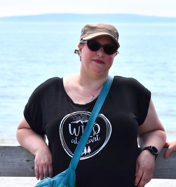 woman in sunglasses, ocean and an island behind her