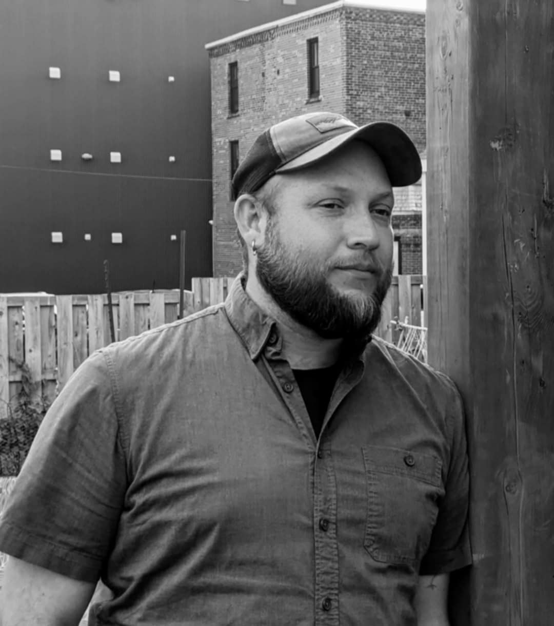 Scott looking serious, outdoors, baseball cap and collar shirt