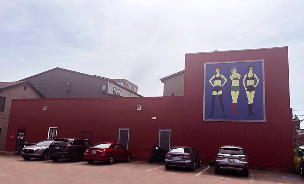 exterior of building with a mural, three partially clad female figures 