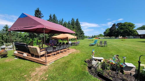 back lawn with a deck with a canopy over it, and chairs around a table