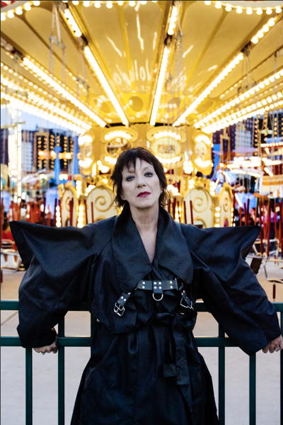 Carole in a huge black buckled leather jacket with enormous shoulders