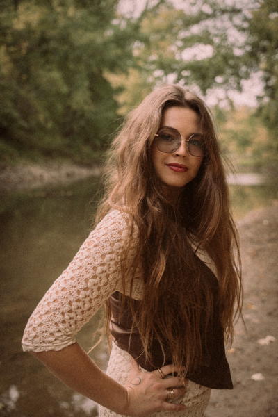 Kylie in a forest,with a river behind