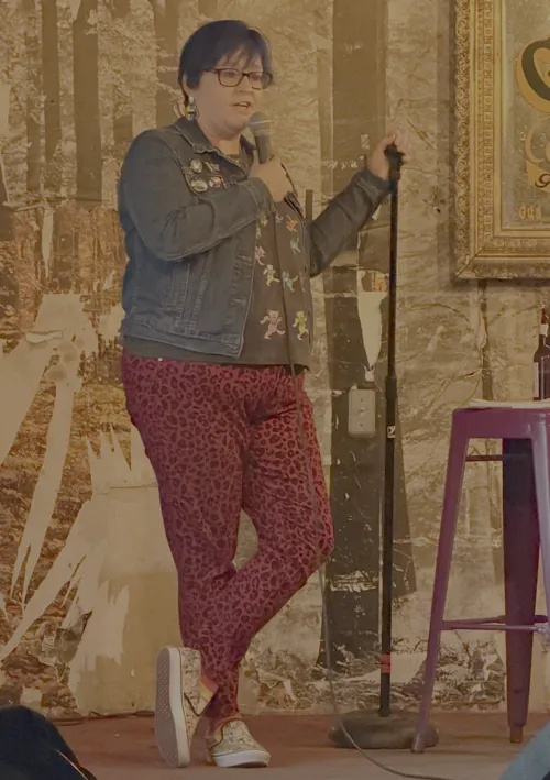 Catherine in red leopard print on stage with a mic